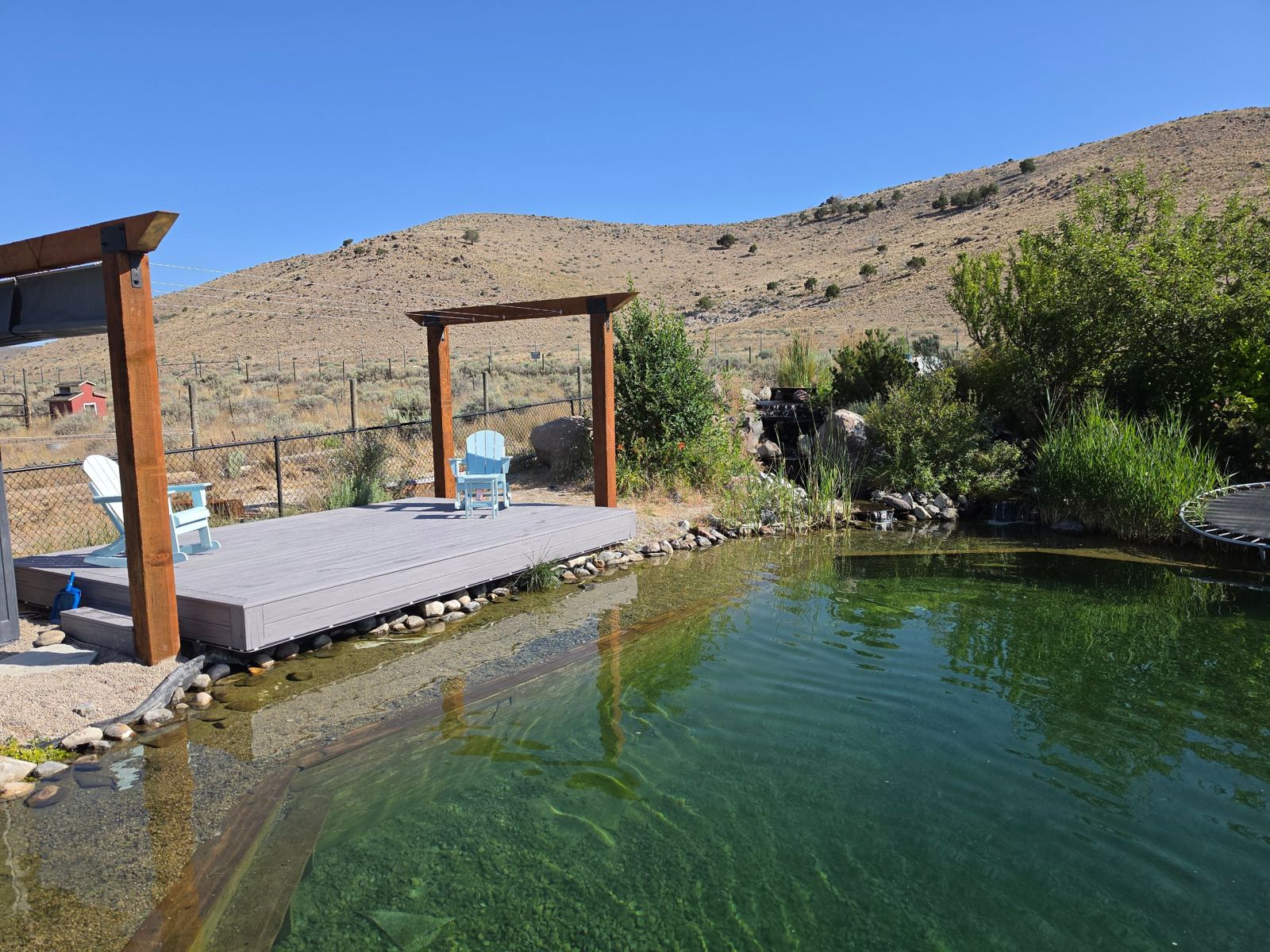Shaded gray PVC deck beside clear green water